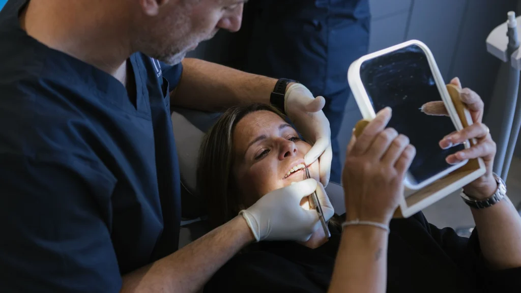 Dentista explicant com revisar genives sagnants amb un model dental en una consulta lluminosa.
