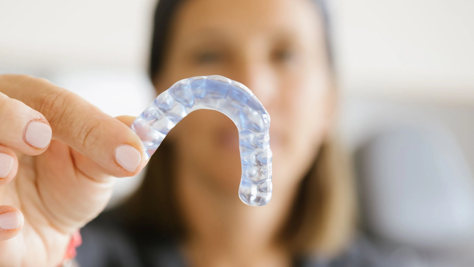 Bruxisme en dormir amb pacient que es desperta amb tensió mandibular i dentista revisant desgast dental