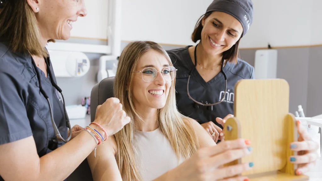 Dentista explicant un blanquejament dental abans de l’estiu amb guia de color en una consulta lluminosa